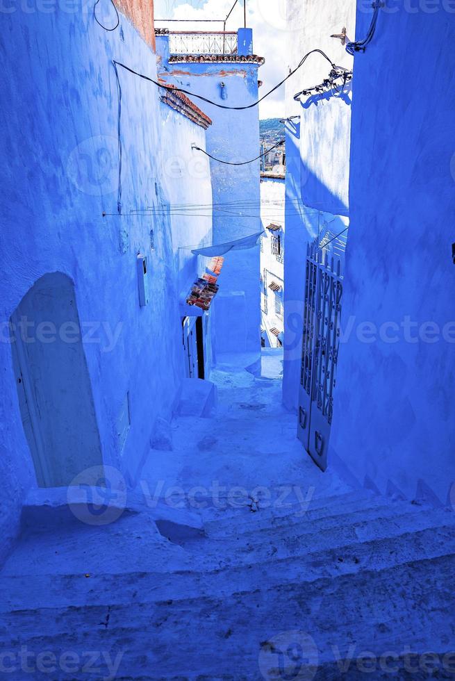 smal steegje van blauwe stad met trap die aan beide kanten naar woonstructuren leidt foto