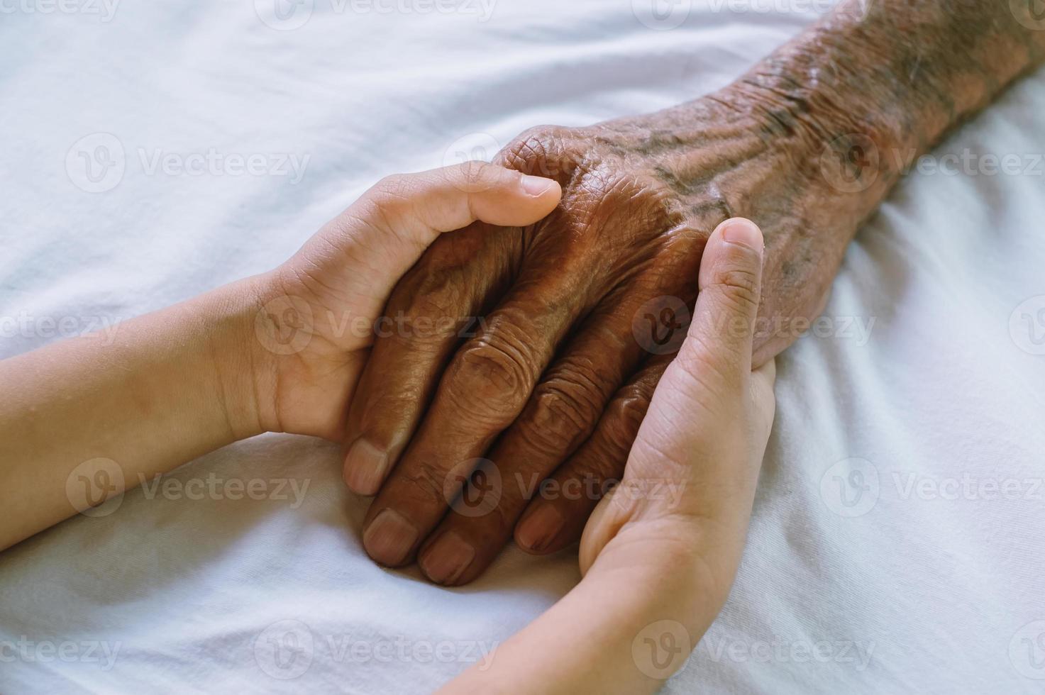 handen van de oude man en de hand van een kind op de kamer foto