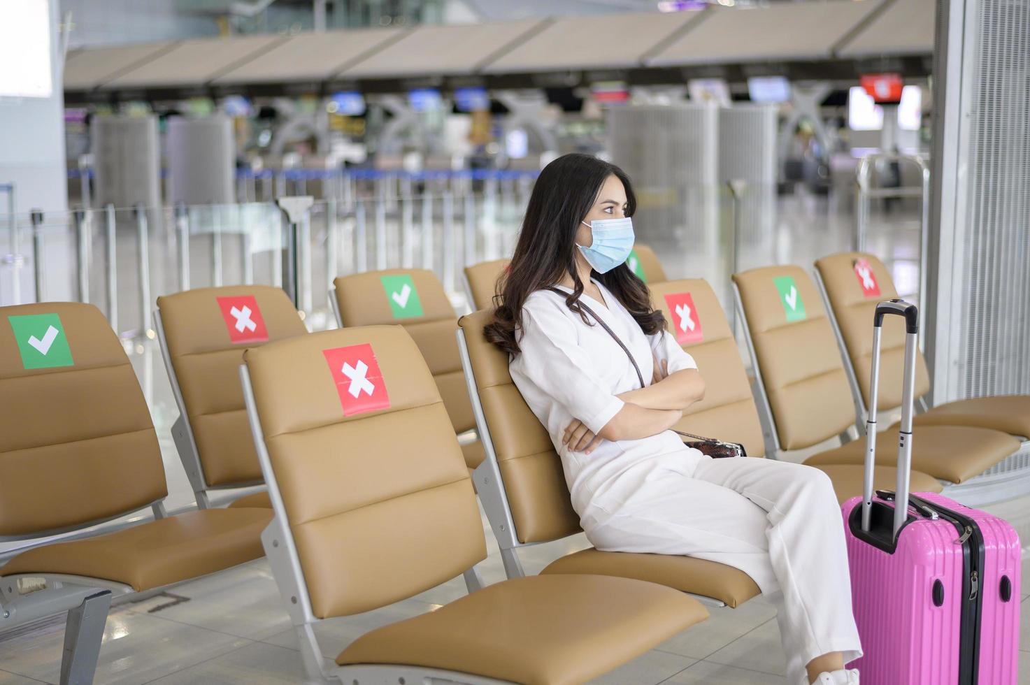 een reizigersvrouw draagt een beschermend masker op de internationale luchthaven, reist onder covid-19 pandemie, veiligheidsreizen, protocol voor sociale afstand, nieuw normaal reisconcept foto