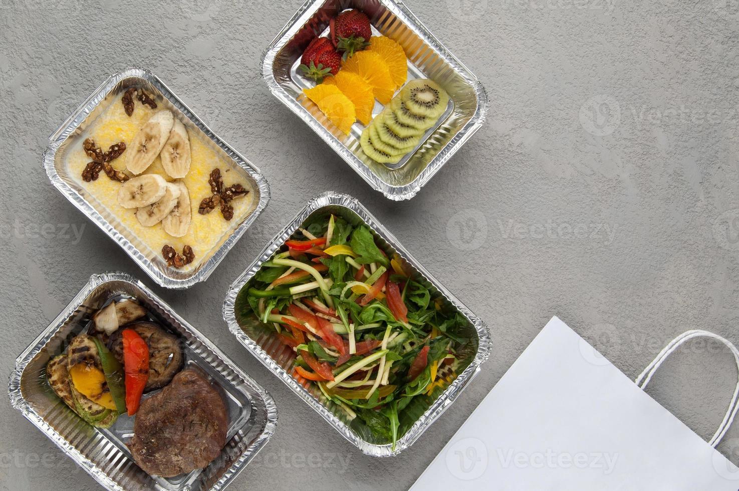 fastfood in een foliedoos op een grijze achtergrond. een gezonde voeding close-up. bezorging van het restaurant een set van gezonde voeding foto