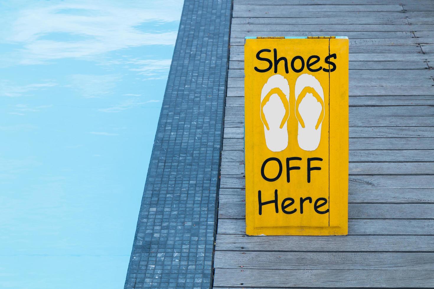 geen schoenen ondertekenen waarschuwing bij het zwembad op de houten vloer foto