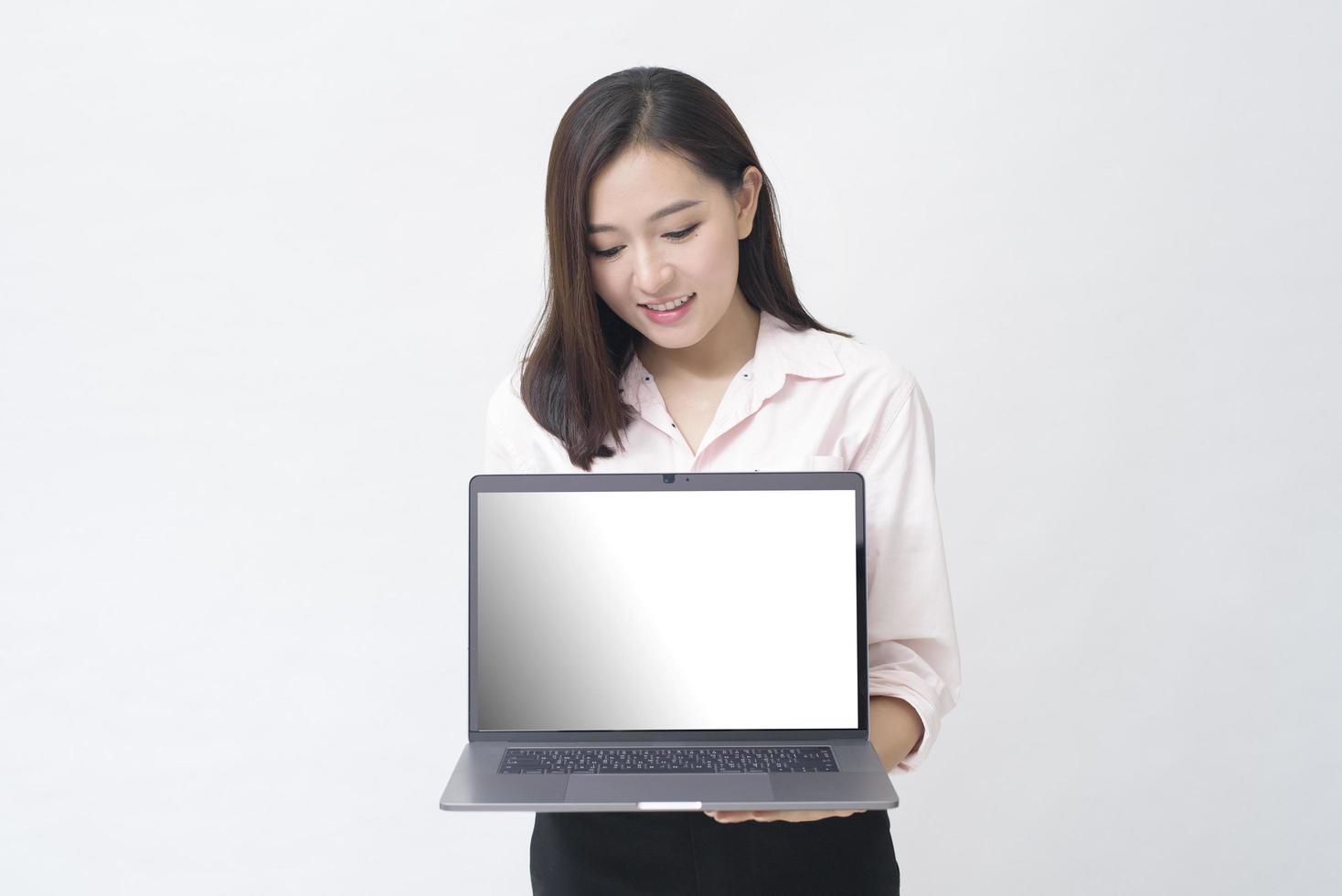 een Aziatische vrouw houdt een laptopcomputer op een witte studioachtergrond foto