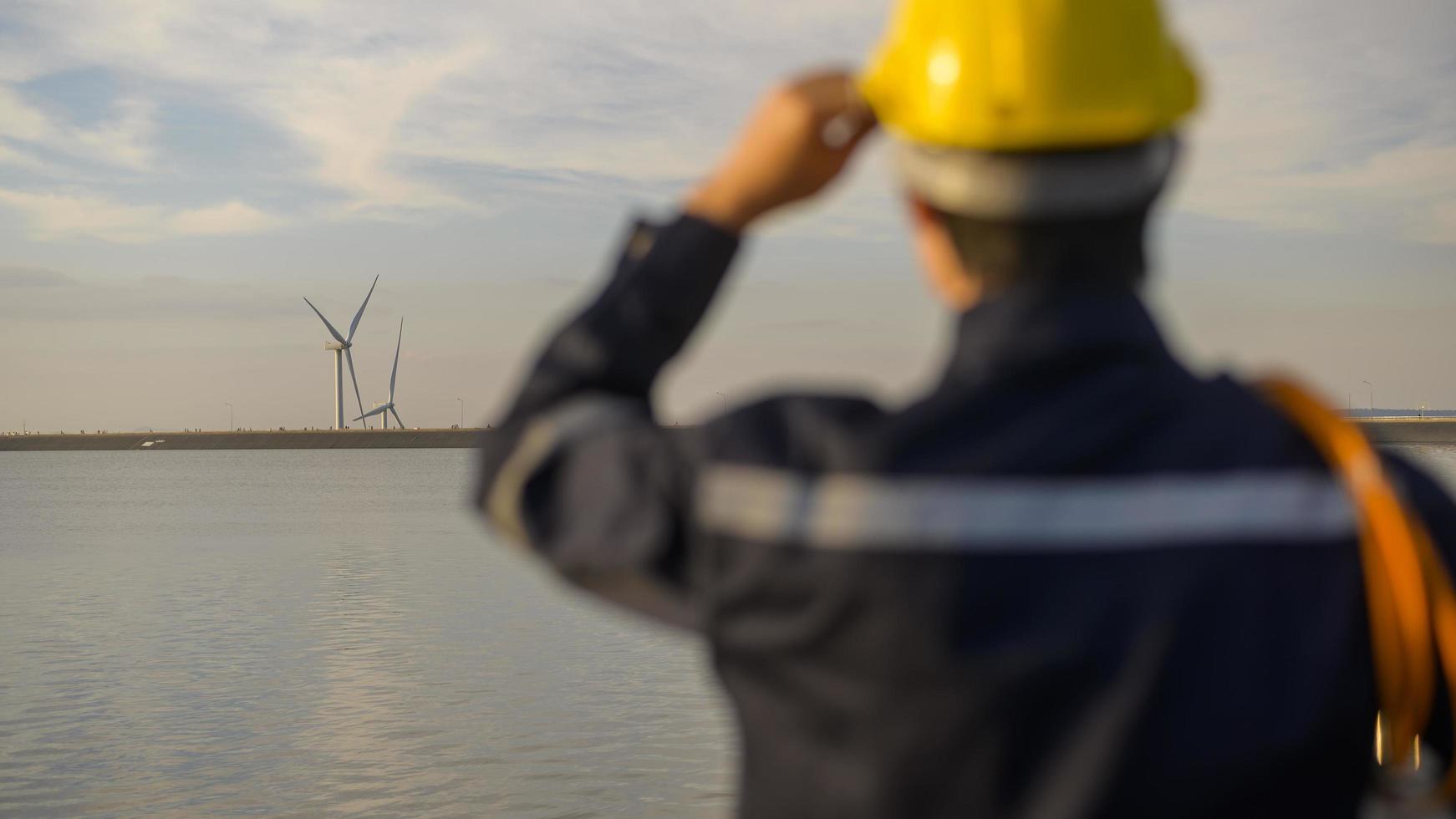 een mannelijke ingenieur die een beschermende helm draagt bij zonsondergang, selectieve focus op achtergrond foto