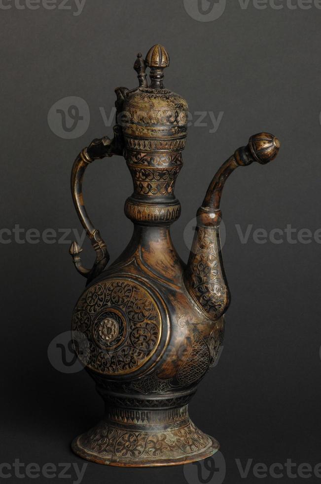 oude oosterse metalen theepot op donkere achtergrond. antiek bronzen servies foto