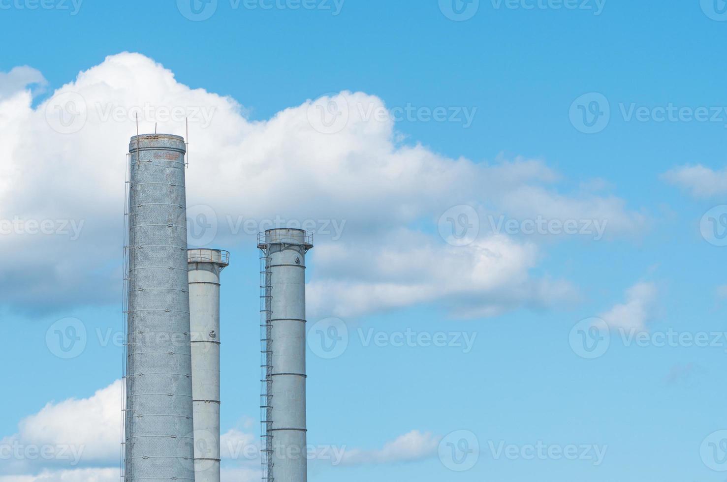 pijpen van een industriële onderneming tegen een blauwe lucht met wolken. schoorsteen zonder rook foto