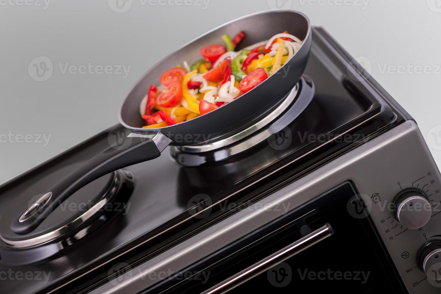 groenten in een koekenpan worden gekookt op een modern elektrisch fornuis. keuken apparatuur foto