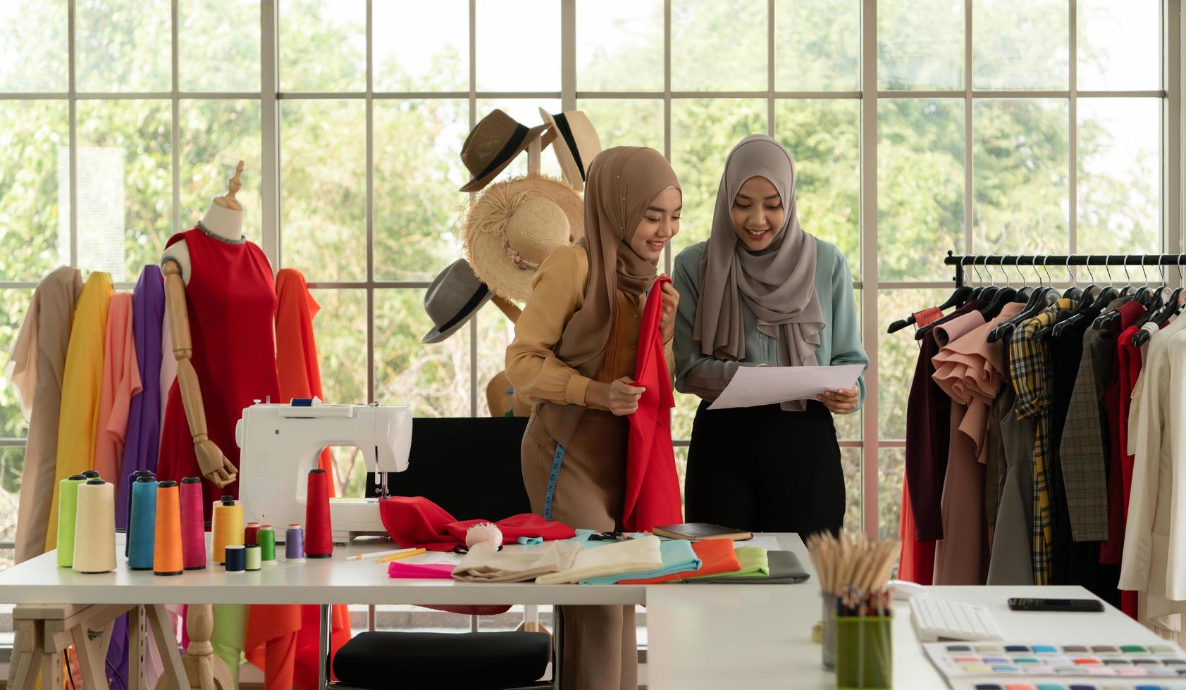 beide moslimvrouwen runnen een klein bedrijfje in hun eigen huis. is het ontwerpen en afstemmen van kleding. foto