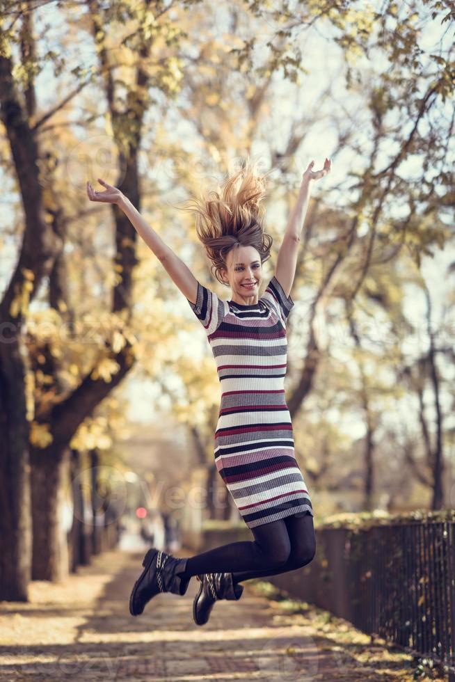 jonge blonde vrouw die op straat springt foto