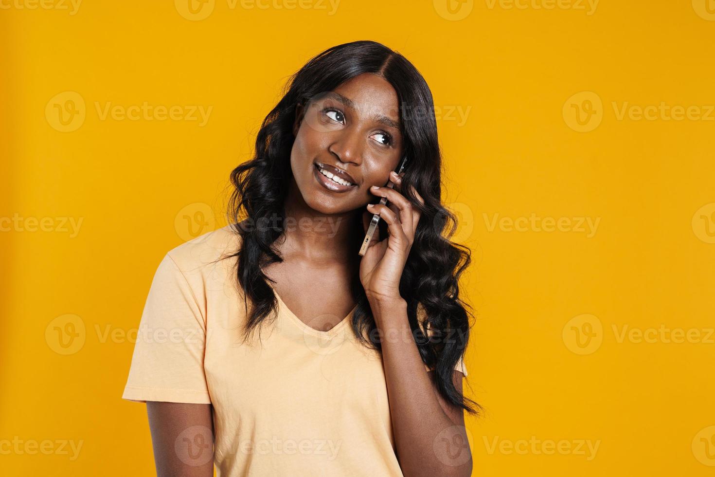 vrolijke afrikaanse vrouw die aan de telefoon praat foto