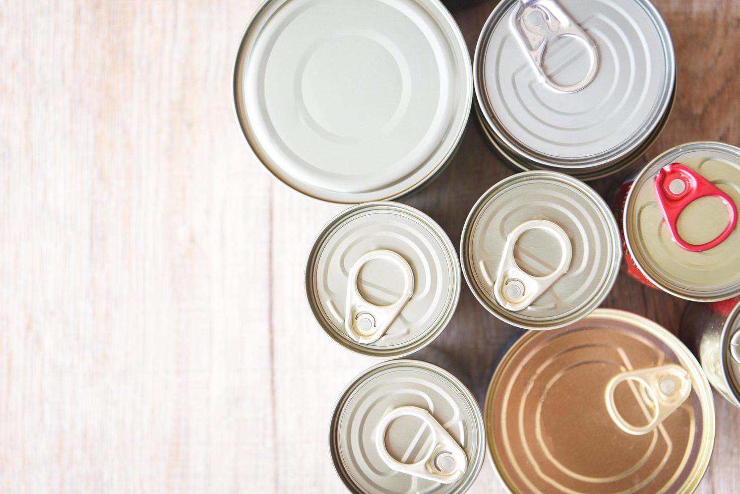 verschillende ingeblikt voedsel in metalen blikken op houten achtergrond, bovenaanzicht ingeblikte goederen niet-bederfelijke voedselopslag goederen in de keuken thuis of voor donaties foto