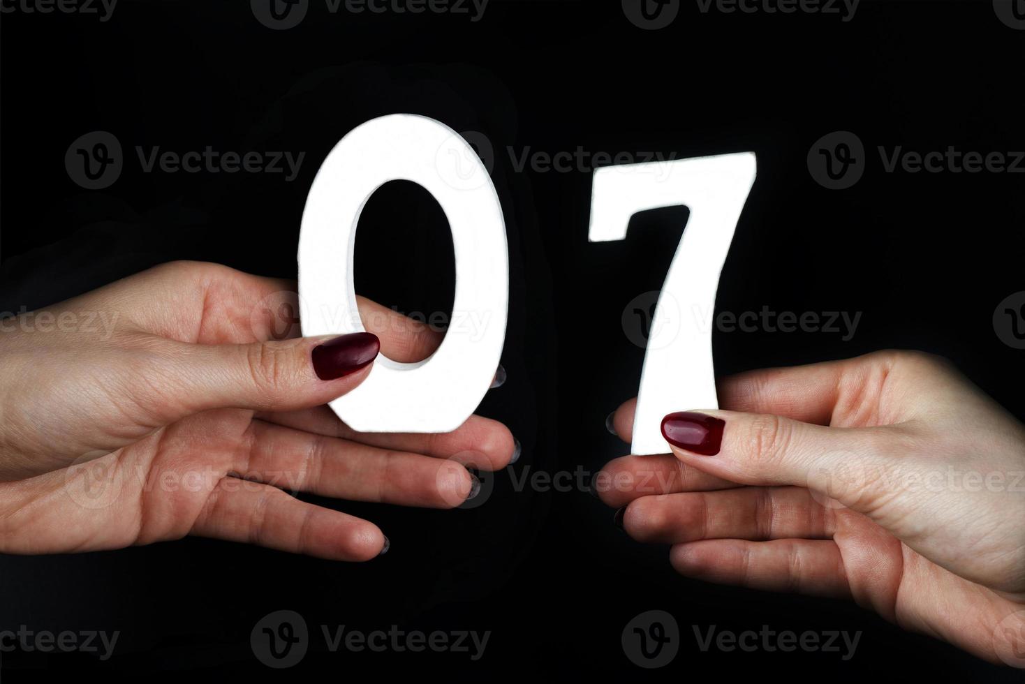 vrouwenhanden houden de nummers nul en zeven vast. foto