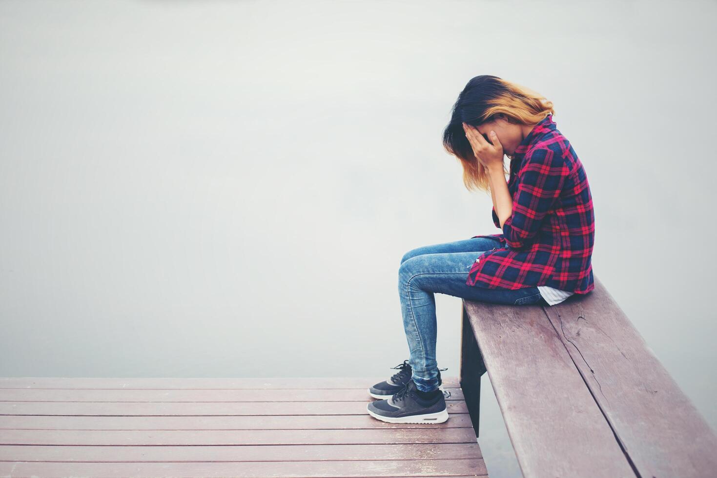 triest hipster vrouw zittend op de pier met verdriet. foto