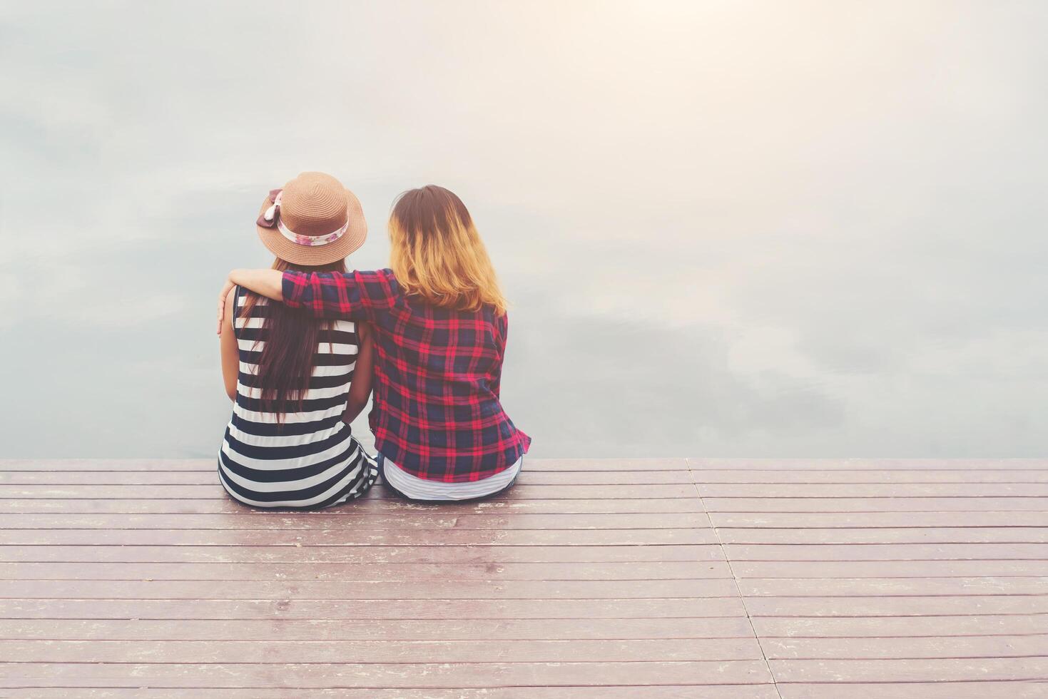 vriendschap, twee vrouwen zitten op de pier, ontspannen en samen tijd doorbrengen. foto