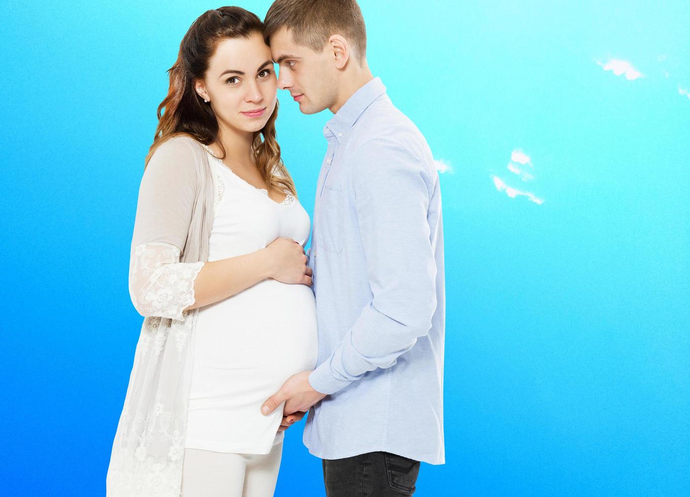 portret van een jong paar in afwachting van het kind geïsoleerd op een blauwe achtergrond, jonge aantrekkelijke paar zwangere moeder en gelukkige vader, mooie jonge paar verwacht baby foto