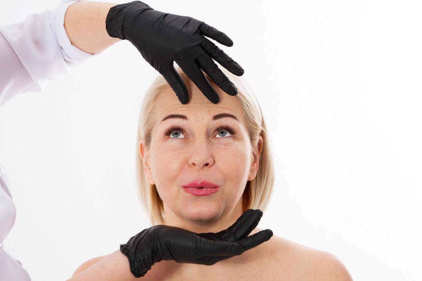 het concept van cosmetica en huidverzorging, veroudering en huidverzorging, blonde vrouw en handen van schoonheidsspecialist chirurg foto