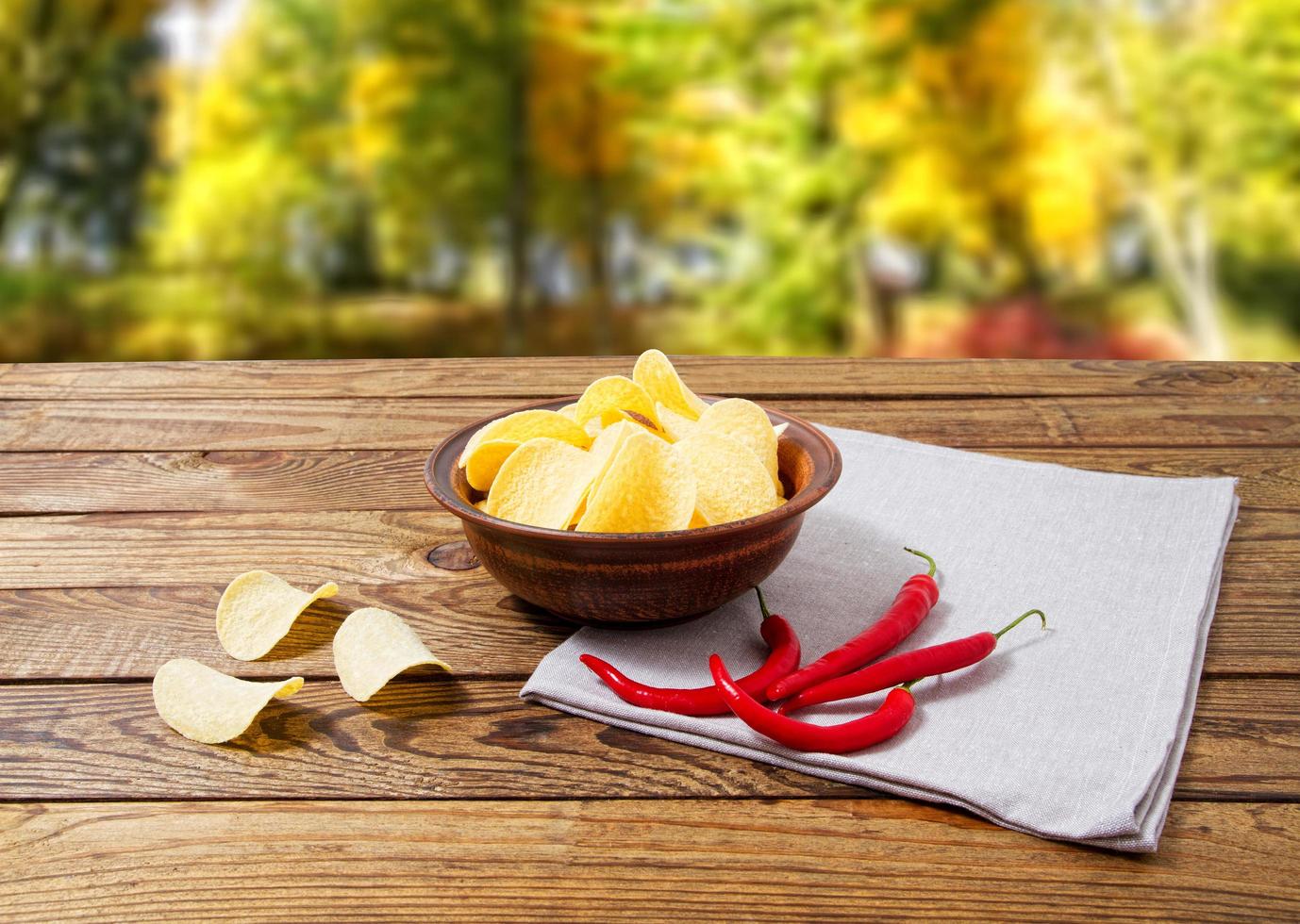 Aardappelchips, servet, hete chili peper op houten tafel op wazig park background.tablecloth, holiday foto