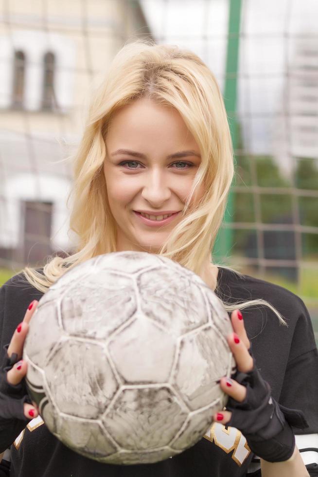 mooie blonde met een bal bij het voetbaldoel. foto