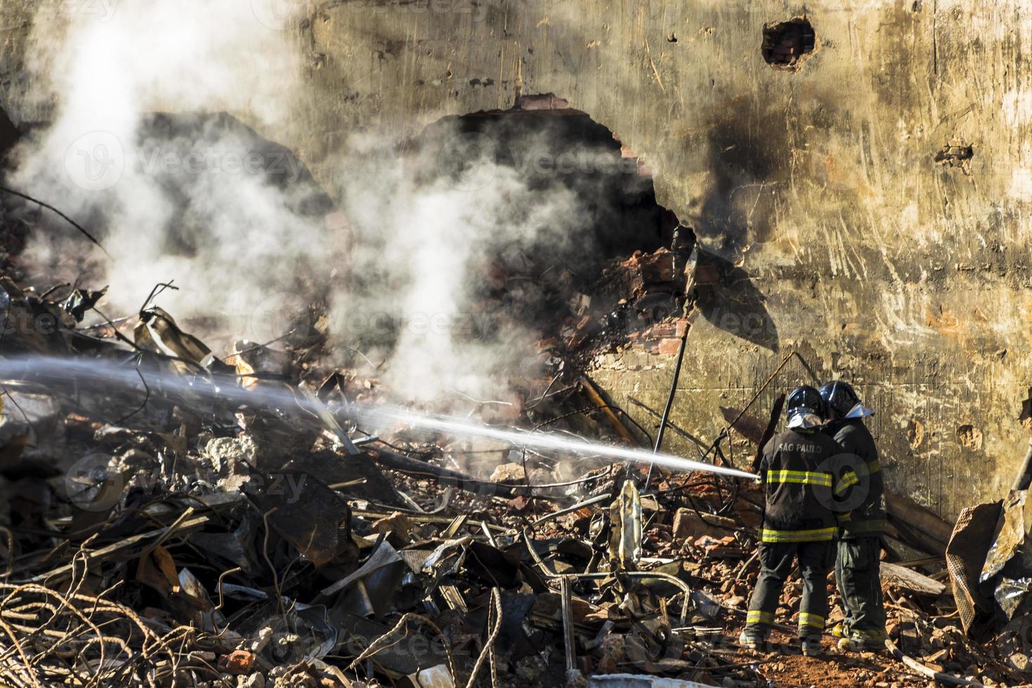 Braziliaanse brandweerman bestrijdt vlammen in het puin waar een gebouw van 24 verdiepingen instortte na een brand foto