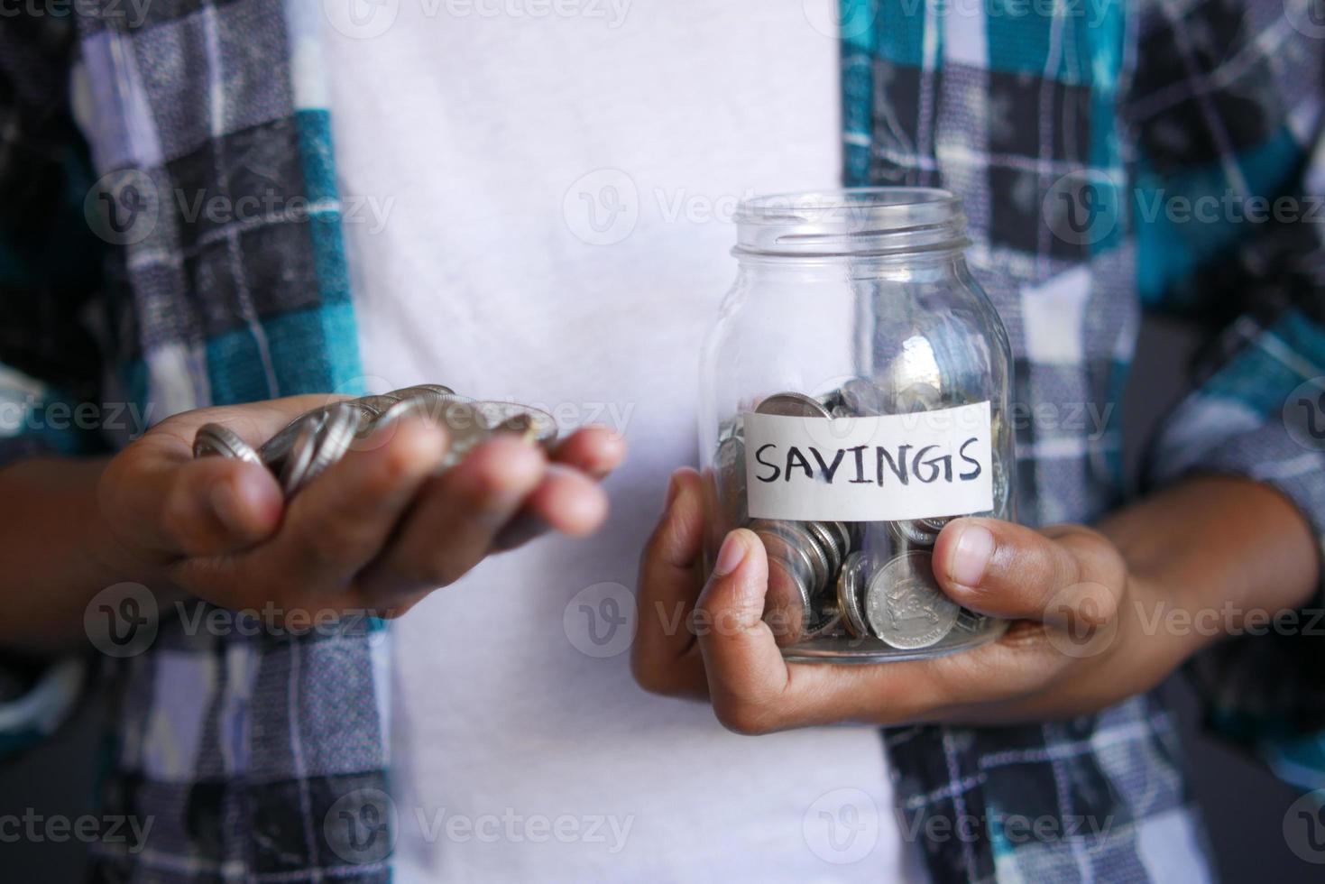 jonge man spaart munten in een witte pot foto