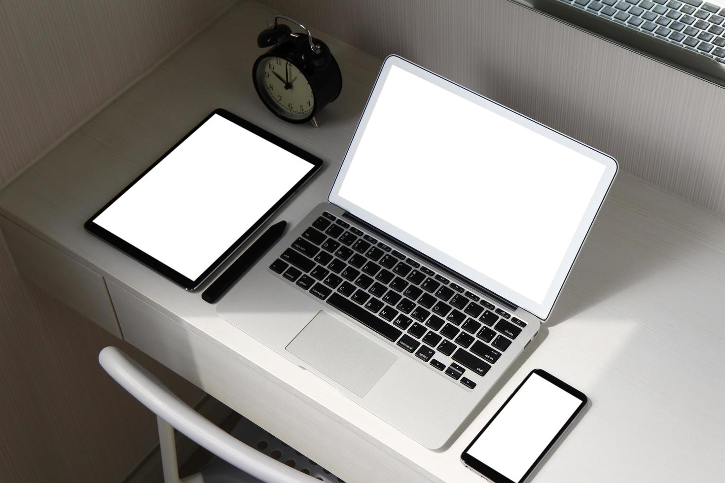 leeg scherm laptopcomputer en smartphone en digitale tablet en stylus pen is op houten bureau als werkplek concept foto