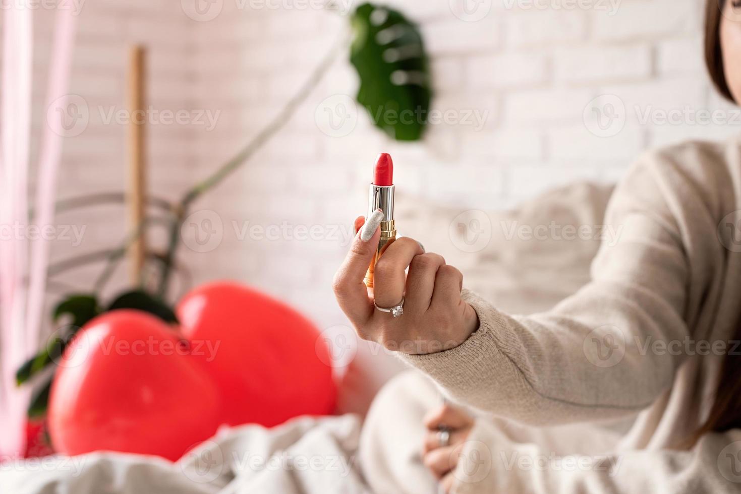 vrouwenhand die rode lippenstift houden foto