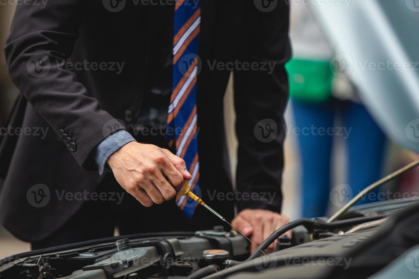 zakenlieden helpen zakenvrouwen bij het controleren en repareren van kapotte auto's foto