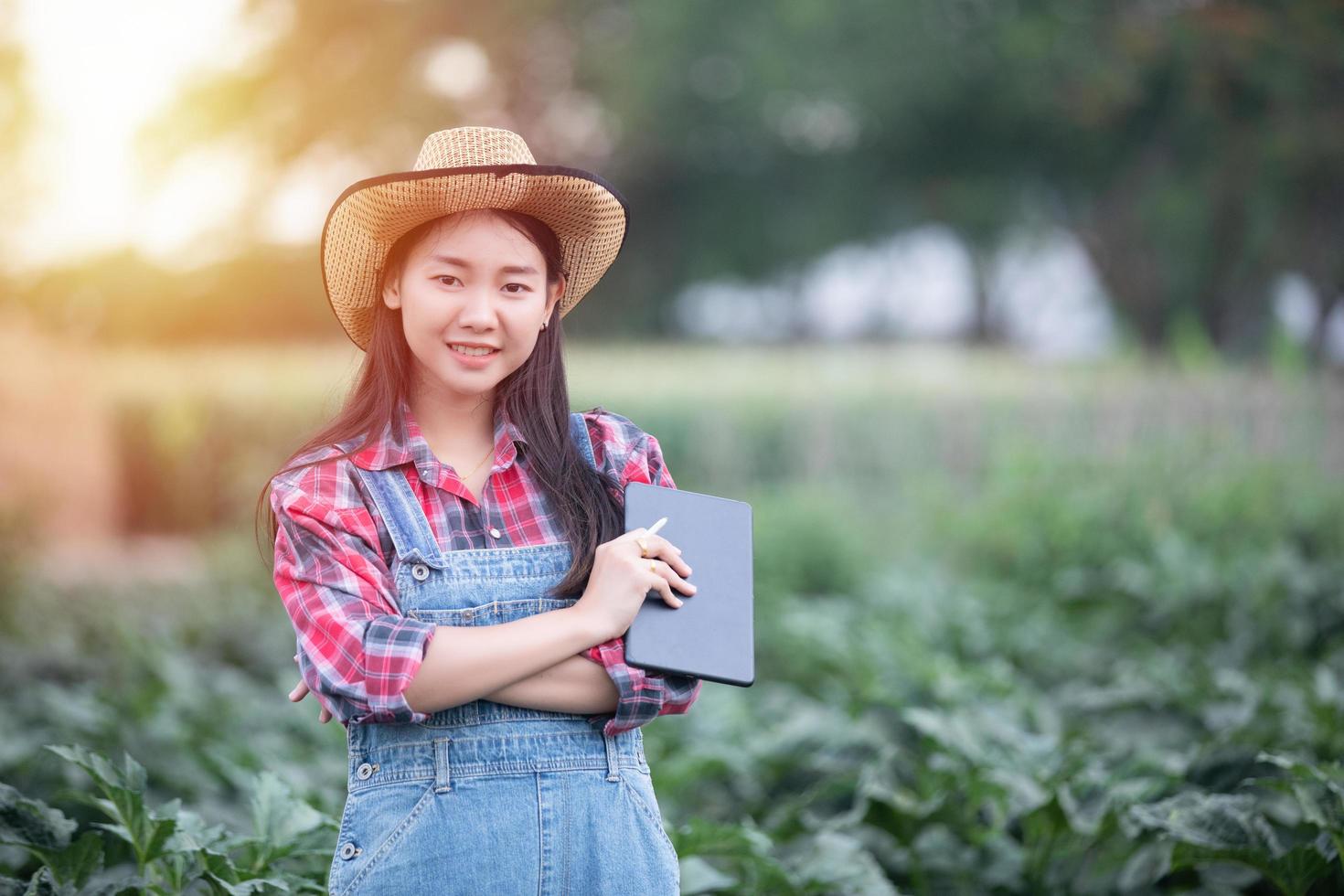 Aziatische vrouwelijke agronoom en boer die technologie gebruikt voor inspectie op agrarisch en biologisch groentegebied foto