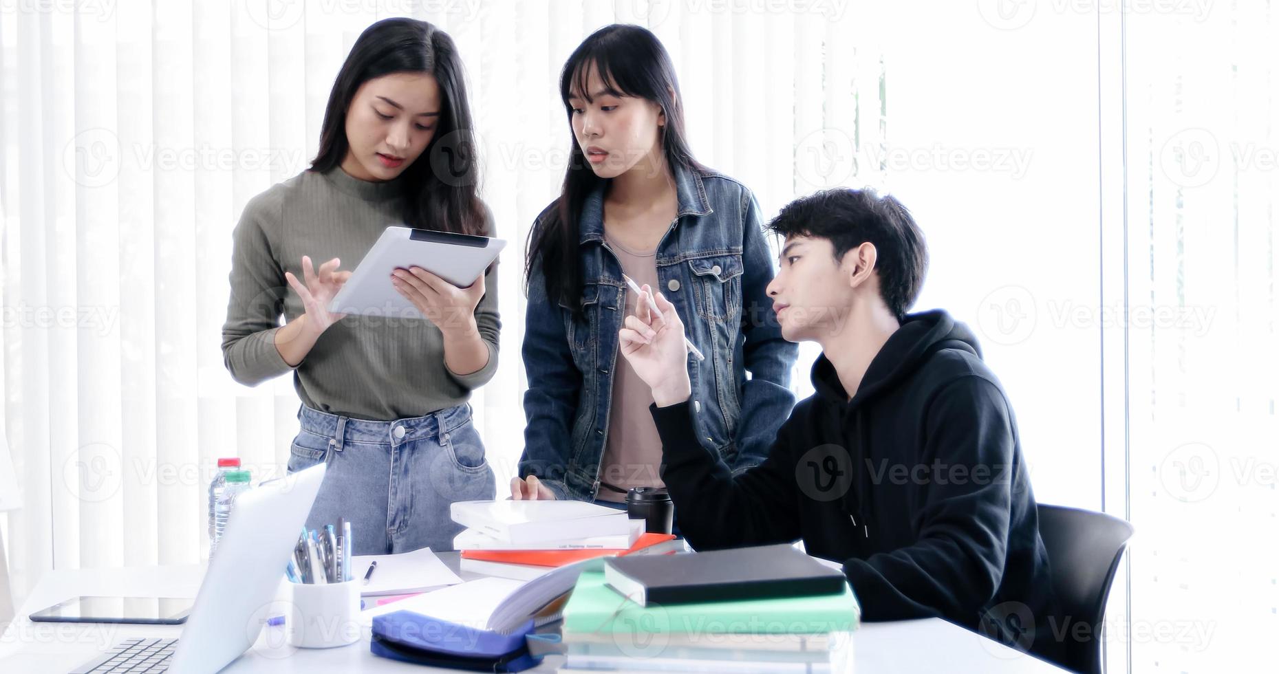 Groepsstudenten lachen en hebben plezier en het gebruik van een tablet helpt ook om ideeën te delen in het werk en het project. en bekijk ook het boek voor het examen foto