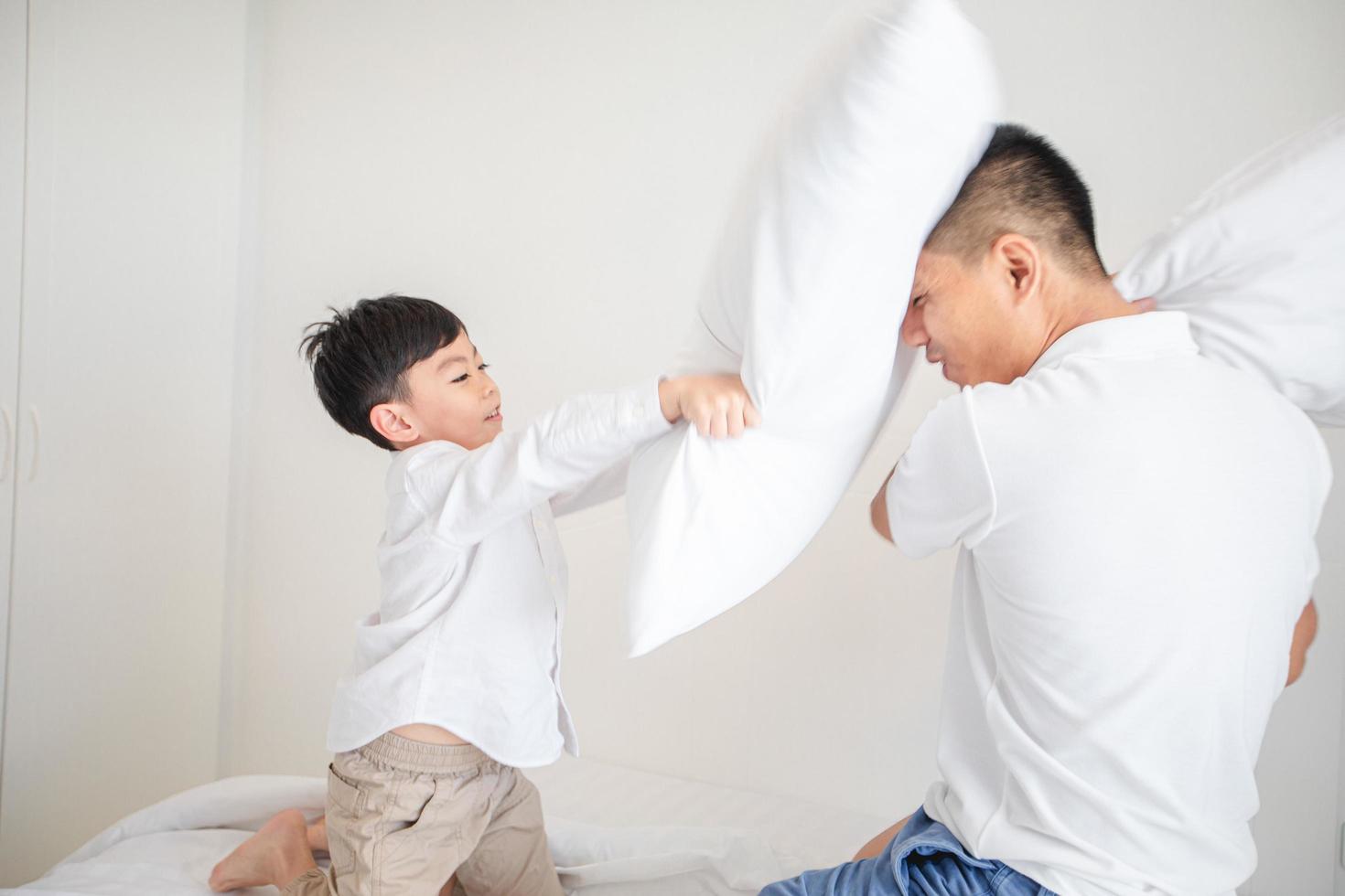 gelukkige Aziatische familie met zoon thuis op de slaapkamer die speelt en lacht foto