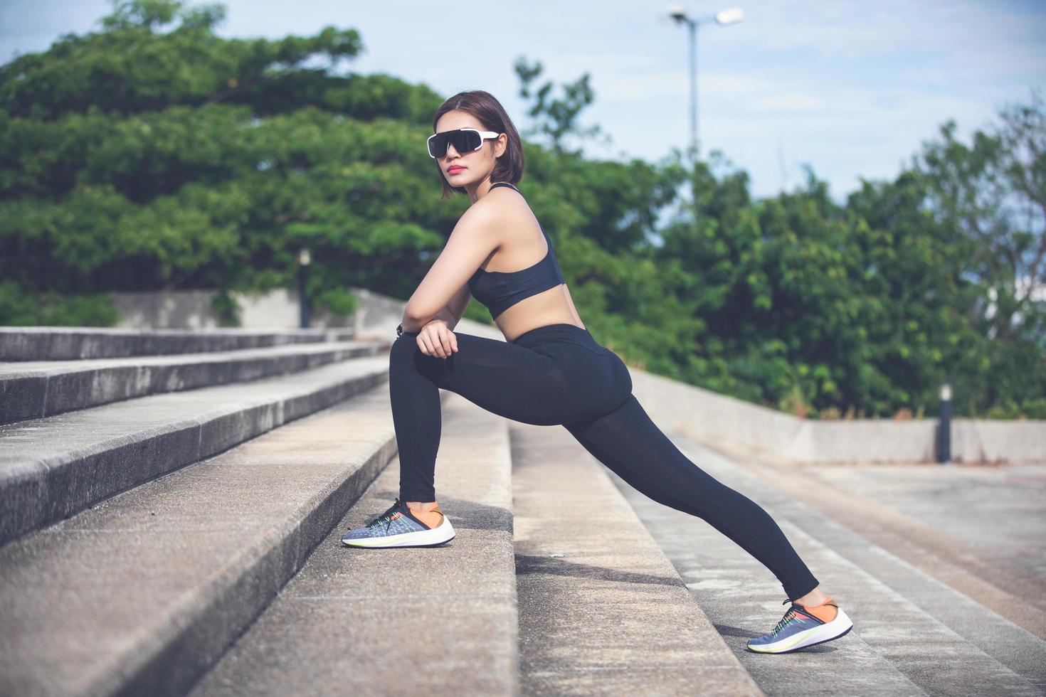 atletische vrouw aziatische warming-up en jonge vrouwelijke atleet zittend op een oefening en stretching in een park voor loper buitenshuis, gezonde levensstijl concept foto