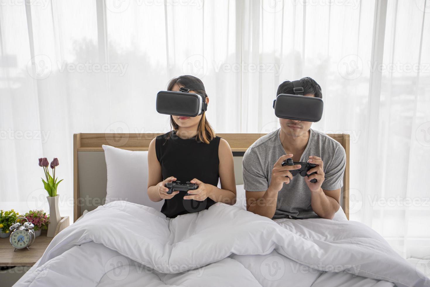 Aziatische paarliefhebber die geniet van het spelen van videogames in de slaapkamer, Aziatische paarliefhebber die zich gelukkig plezier en virtual reality voelt, vr samen games spelen terwijl hij in de slaapkamer thuisconcept ligt. foto