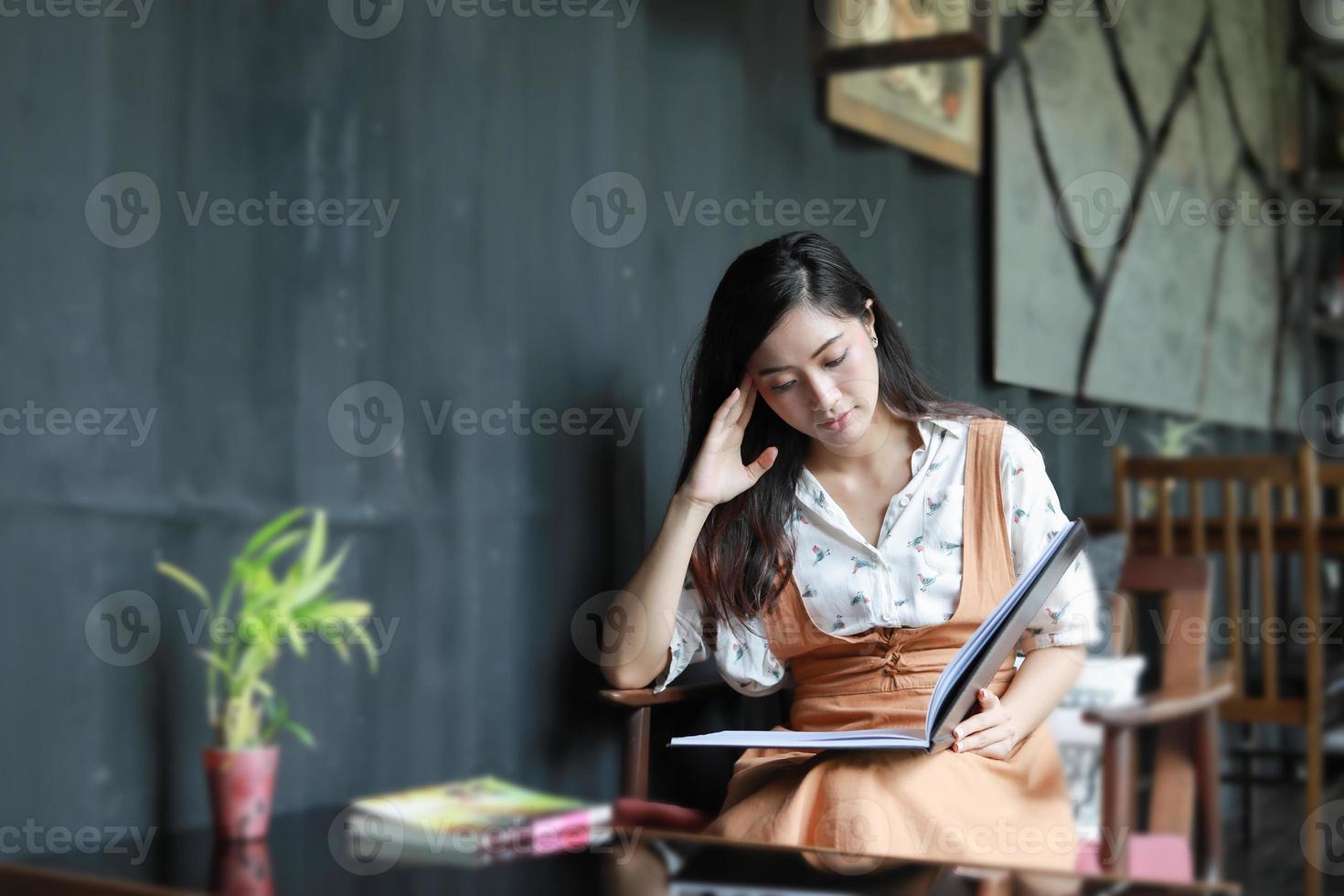 Aziatische vrouwen die een boek lezen en glimlachen en gelukkig ontspannen in een coffeeshop foto