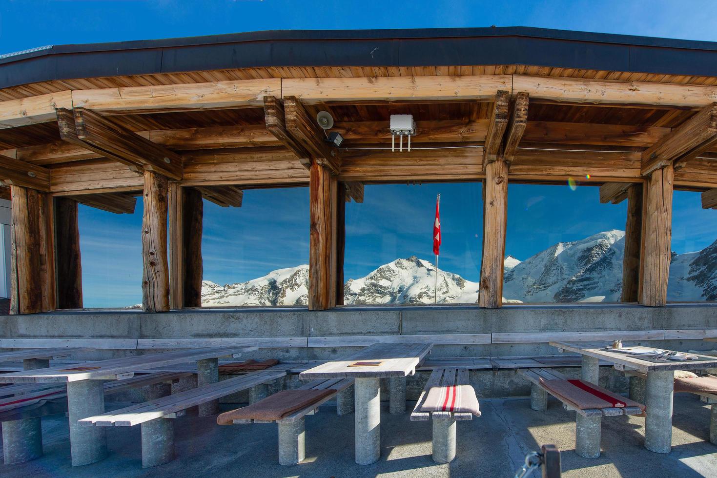 tafels van het restaurant op grote hoogte met uitzicht op het landschap van gletsjers weerspiegeld in glazen ramen in zwitserland. foto