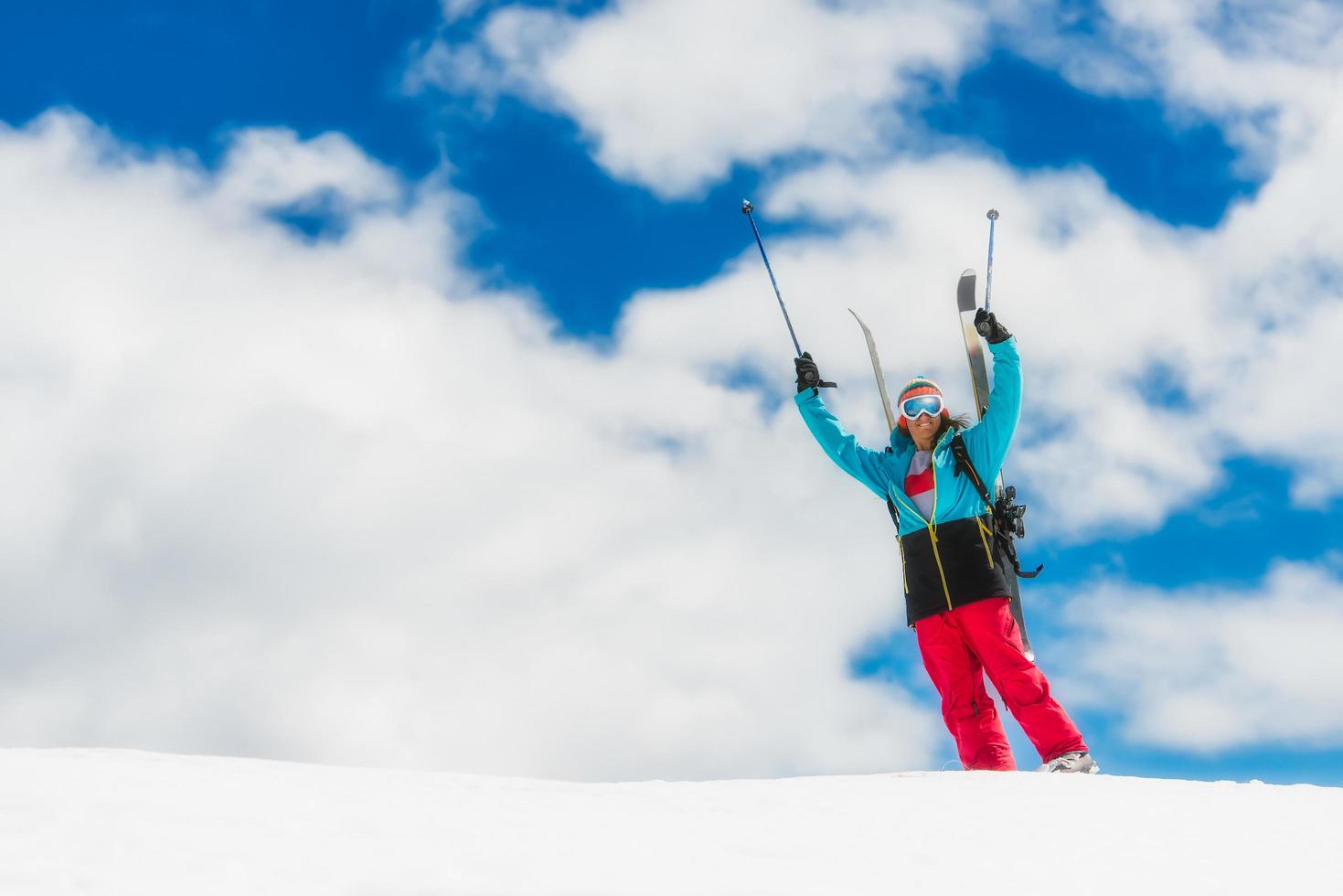 meisje freeride skiër, steekt zijn handen op voor de afdaling van de top foto