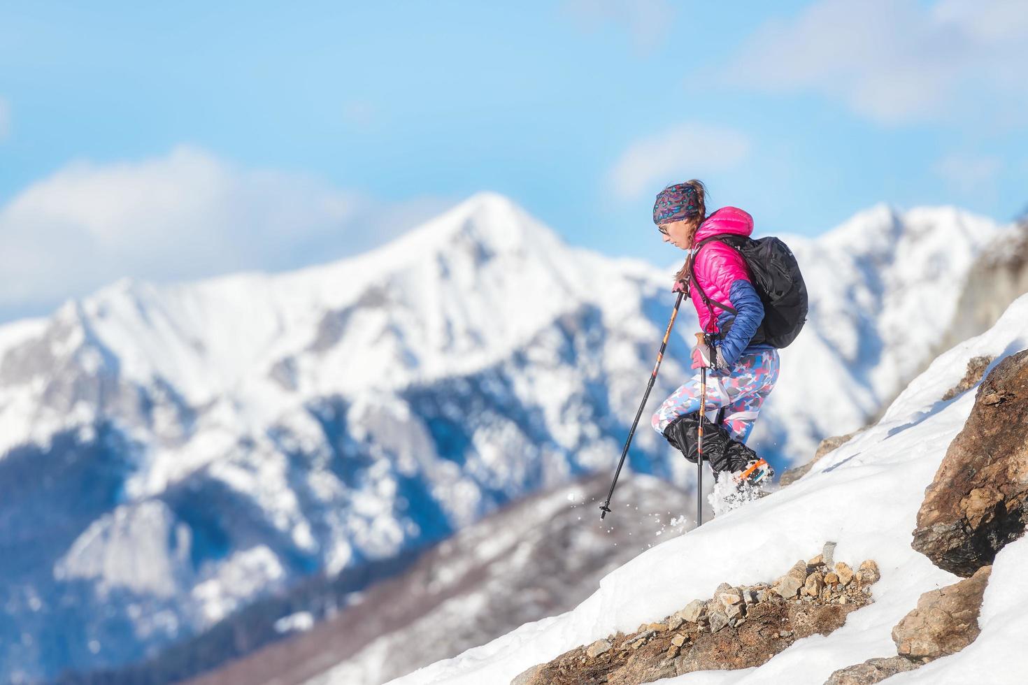vrouw bergbeklimmer bergafwaarts met stijgijzers op besneeuwde helling foto