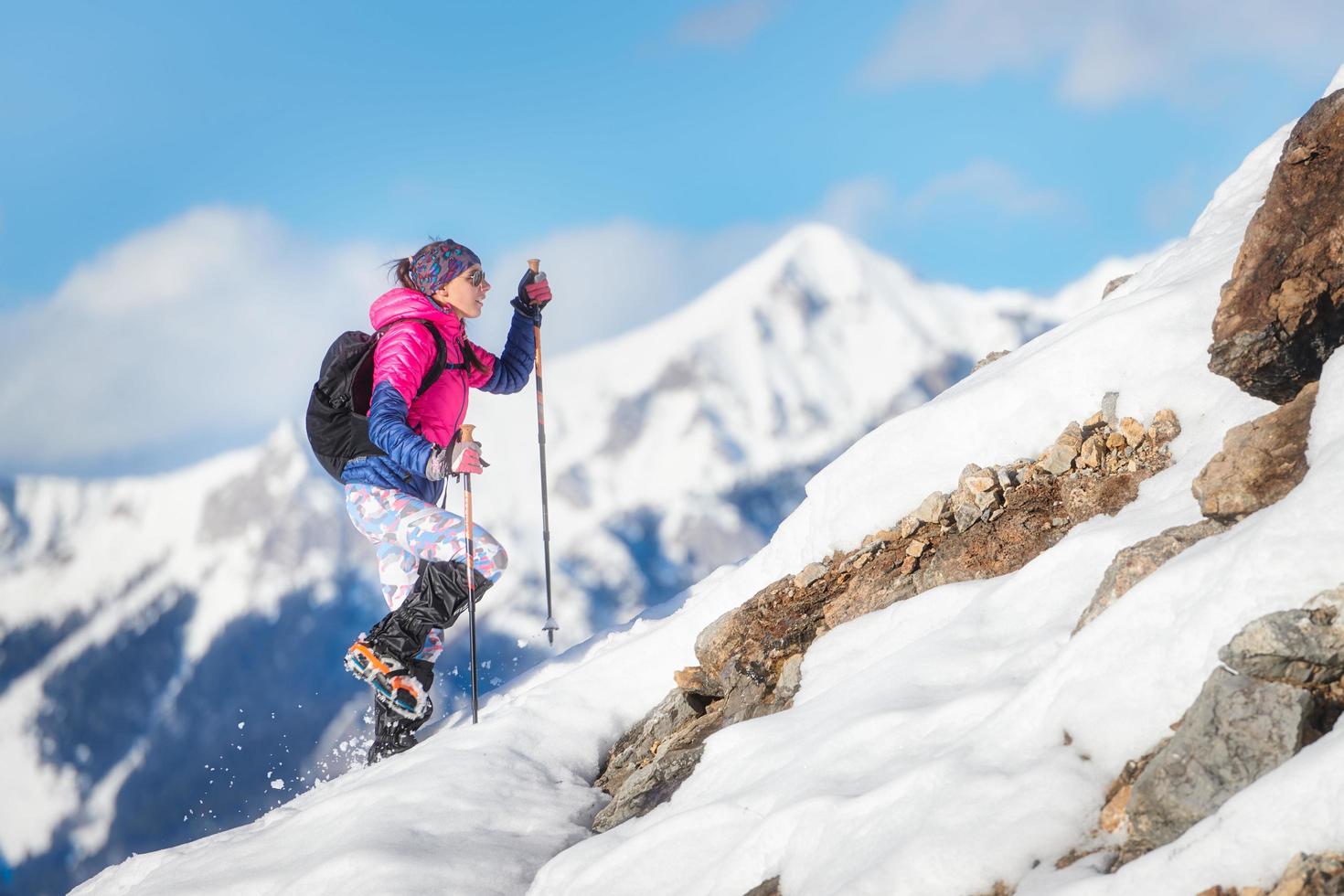vrouw bergbeklimmer tijdens een afdaling met stijgijzers op besneeuwde helling foto