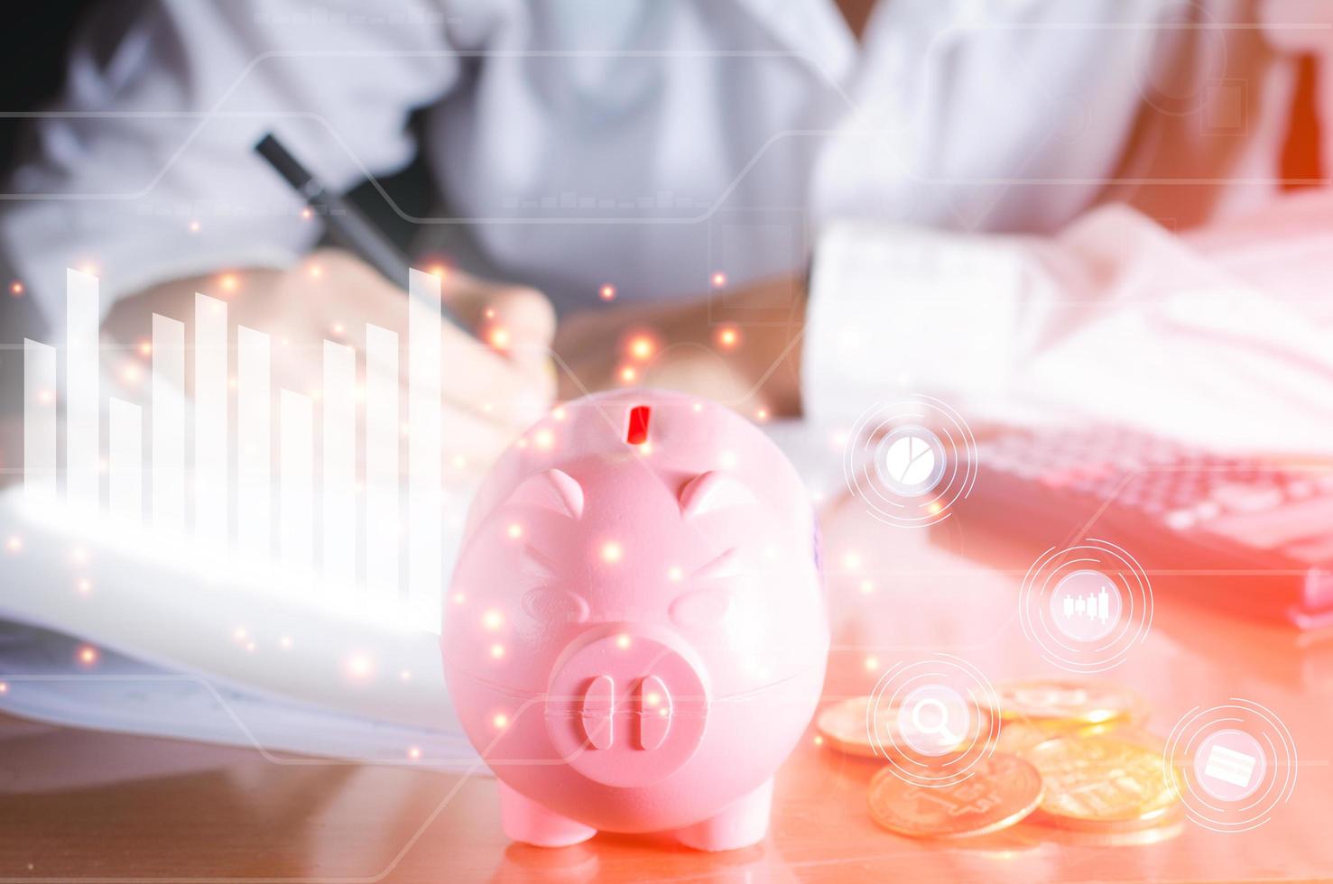 bedrijfs- en analyseconcept. roze spaarvarken op houten tafel met witte grafiek en grafiek icoon analyse financieel op virtueel scherm, positieve groei van geld en aandelen. foto