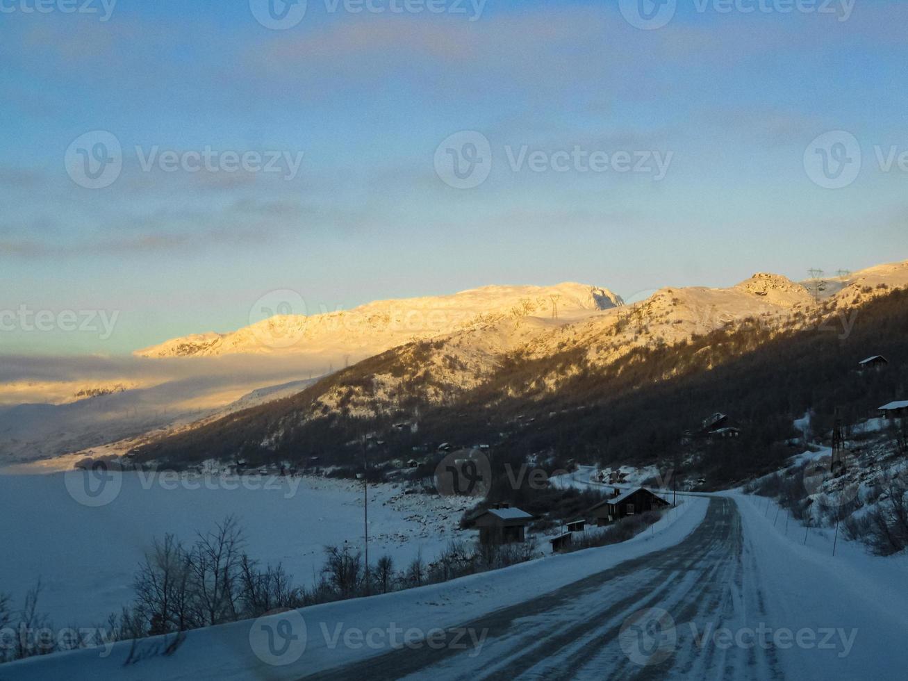 rijden bij gouden zonsopgang door bergen en dorp in noorwegen. foto