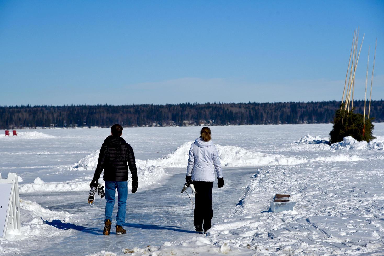 winter in Manitoba - een stel met schaatsen loopt op een bevroren meer foto