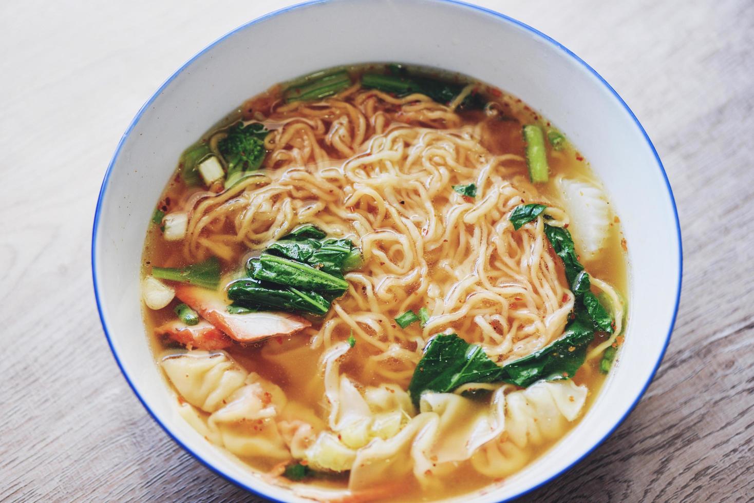 soep noodle wonton varkensvlees gele noedel met rode geroosterde varkensvlees knoedel en bog choy chinese groente in soepkom op houten tafel, bovenaanzicht foto