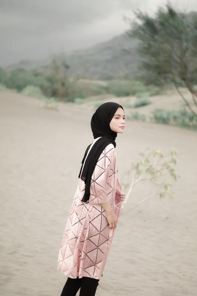 mooi islamitisch vrouwelijk model met hijab-mode, een moderne trouwjurk voor moslimvrouwen loopt langs het zand en de zee. een Aziatisch meisjesmodel dat hijab gebruikt en plezier heeft op het strand. foto prewedding