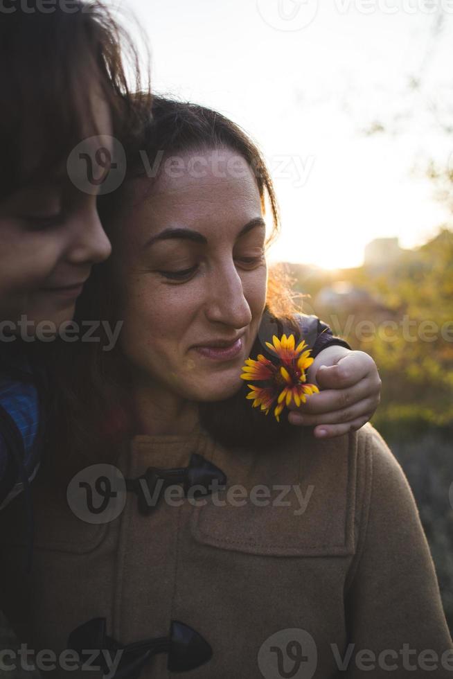 een kind geeft een bloem aan zijn moeder foto