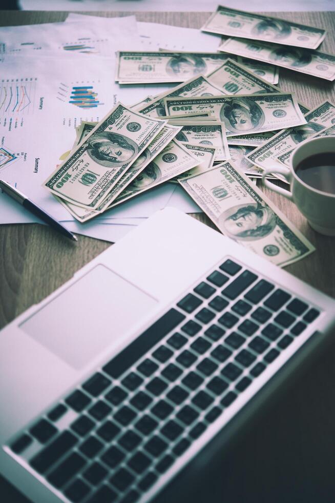 werkplaats van de handelaar. de tafel gedekt door bankbiljetten, toetsenbord en financiële grafieken. zakelijk financieel werken. foto