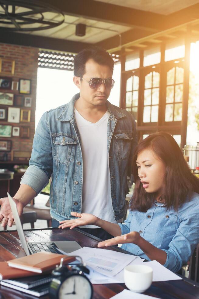 baas schreeuwt tegen een gestresste werknemer wanneer ze met een laptop op kantoor werkt, pratend over niet compleet door werk, zakelijk mislukt concept. foto