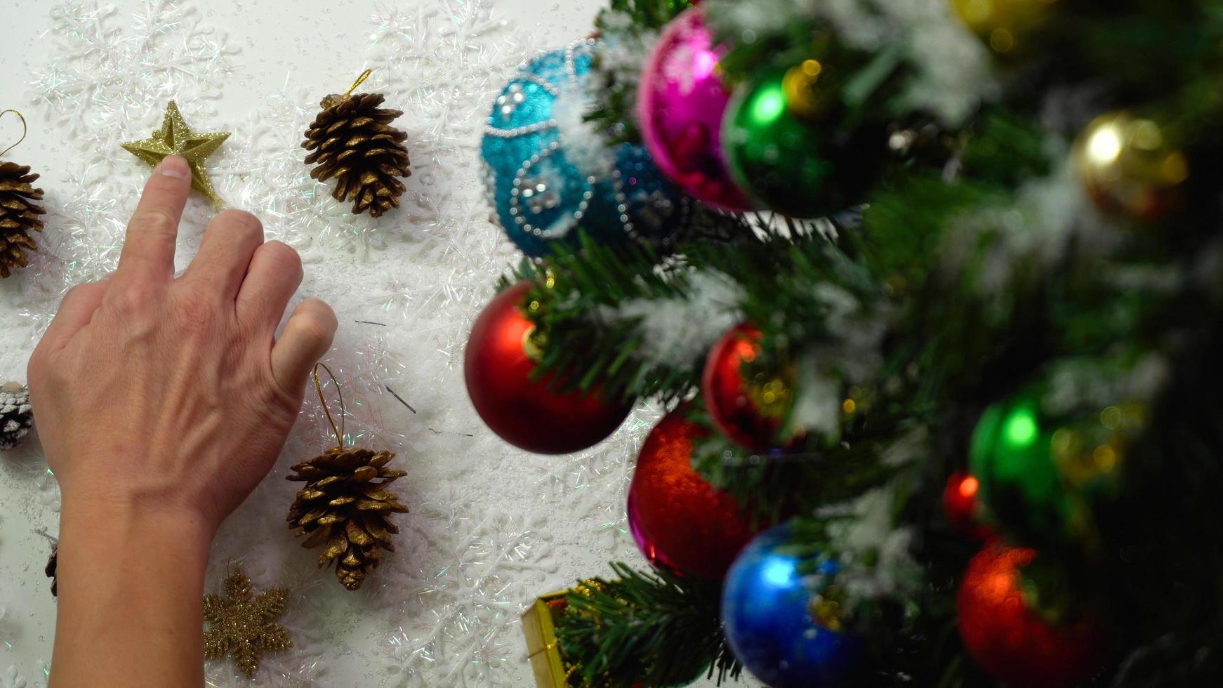 groet seizoen concept.hand instelling van ornamenten op een kerstboom met decoratief licht foto