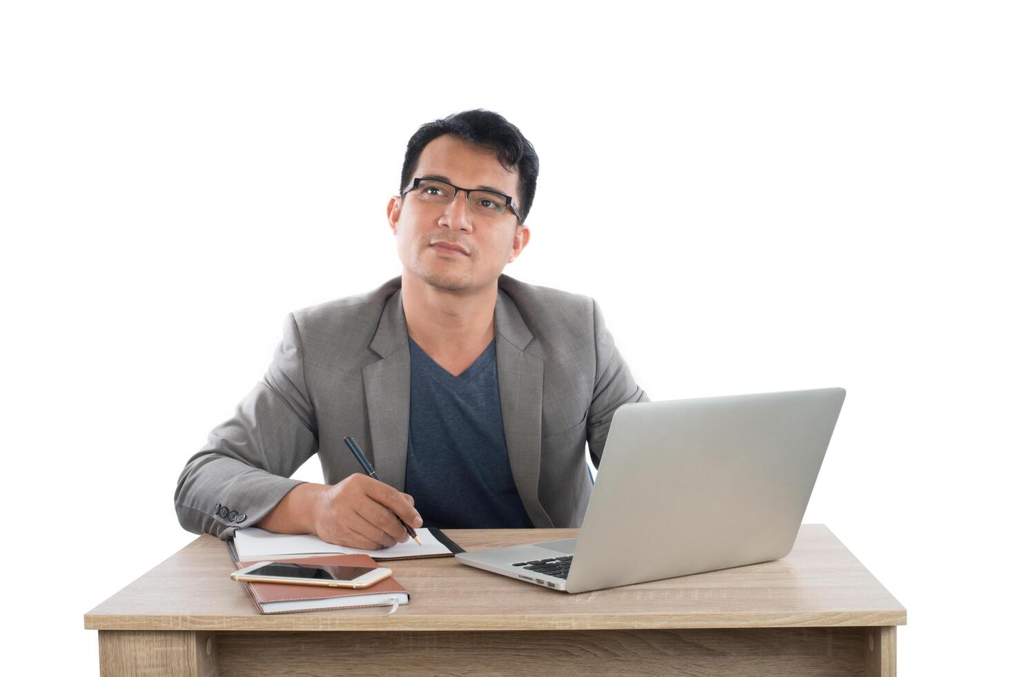 zakenman schrijven van notities op een schrijfblok zittend aan zijn bureau achter zijn nieuwe notebook geïsoleerd op een witte achtergrond. foto