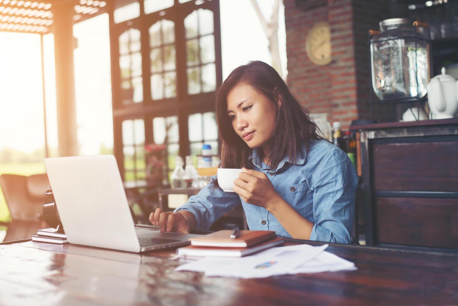 mooie hipster vrouw die laptop gebruikt in café terwijl ze koffie drinkt, ontspannend vakantieconcept. foto