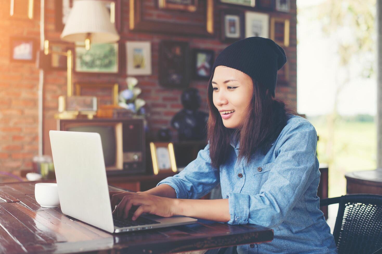 mooie jonge hipster vrouw zitten in een coffeeshop, ontspannen en spelen met haar laptop, informatie vinden over vrije tijd, gelukkig en leuk. levensstijl concept. foto