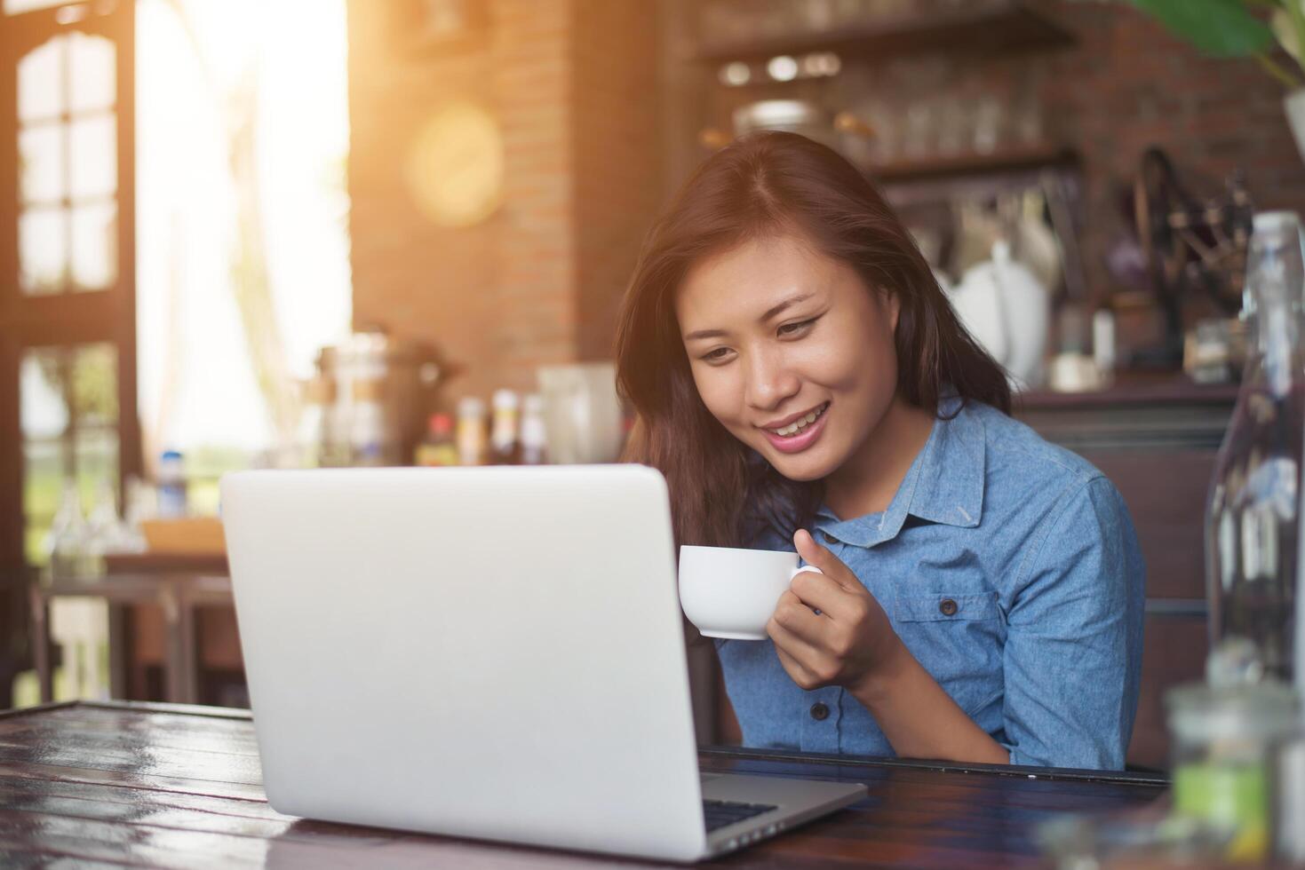 mooie jonge hipster vrouw zitten in een coffeeshop, ontspannen en spelen met haar laptop, informatie vinden over vrije tijd, gelukkig en leuk. levensstijl concept. foto