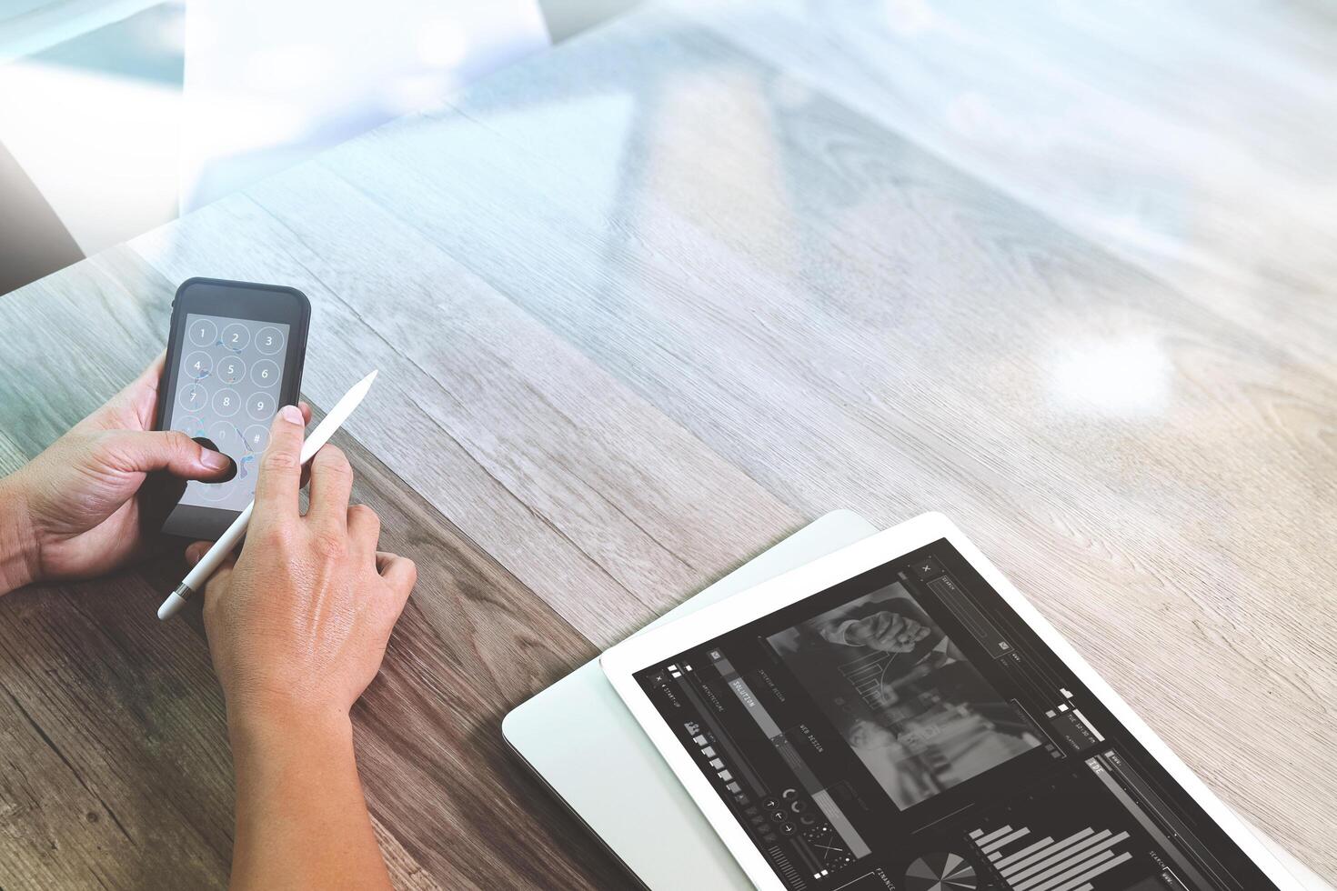 zakenman hand werken met stylus pen digitale tablet slimme telefoon en laptopcomputer. bijwonen van videoconferentie in modern kantoor. op houten bureau. uitzicht vanaf de bovenkant. dubbele belichtingseffecten, minimalisme foto